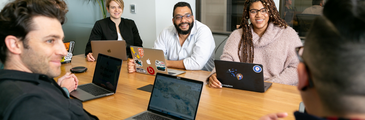 imagem ilustrativa de uma equipe composta por programadores conversando cordialmente ao redor de uma mesa